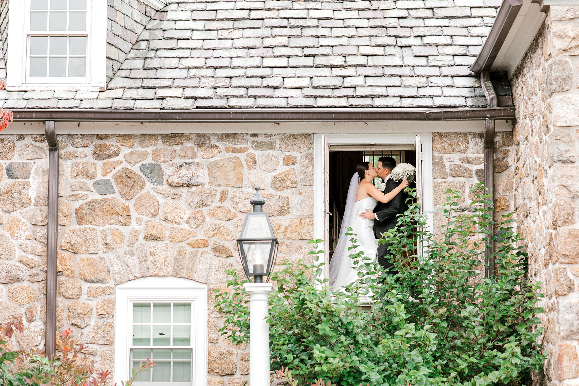 bride and groom hug in doorway of stone building at Fiddler’s Elbow Country Club 