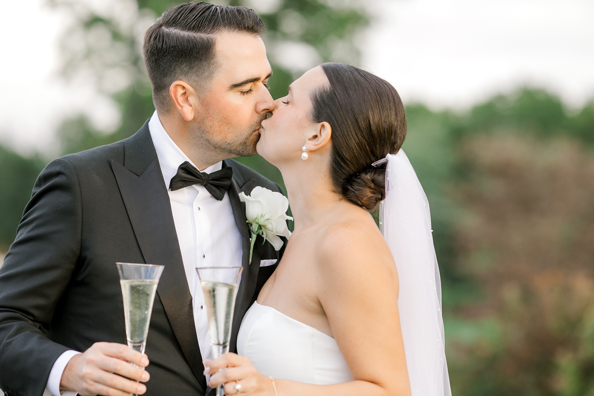bride and groom kiss toasting glasses of champagne