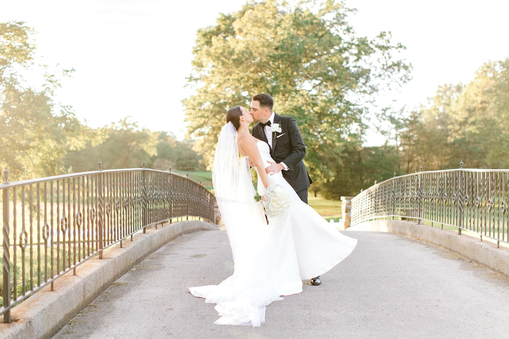 newlyweds kiss and groom dips bride back a little on bridge at Fiddler’s Elbow Country Club 