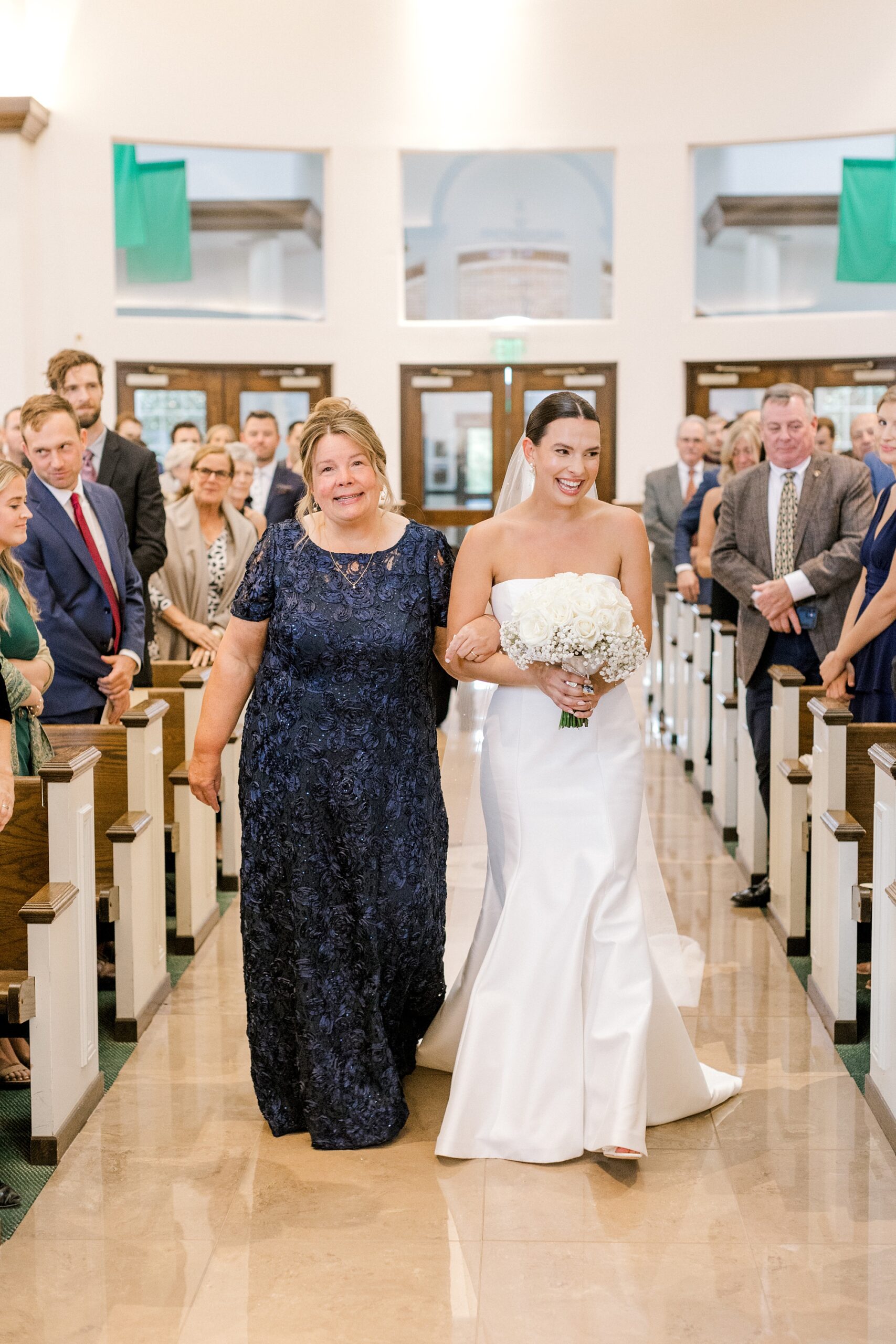 bride and mother walk down aisle for traditional Catholic church wedding in New Jersey