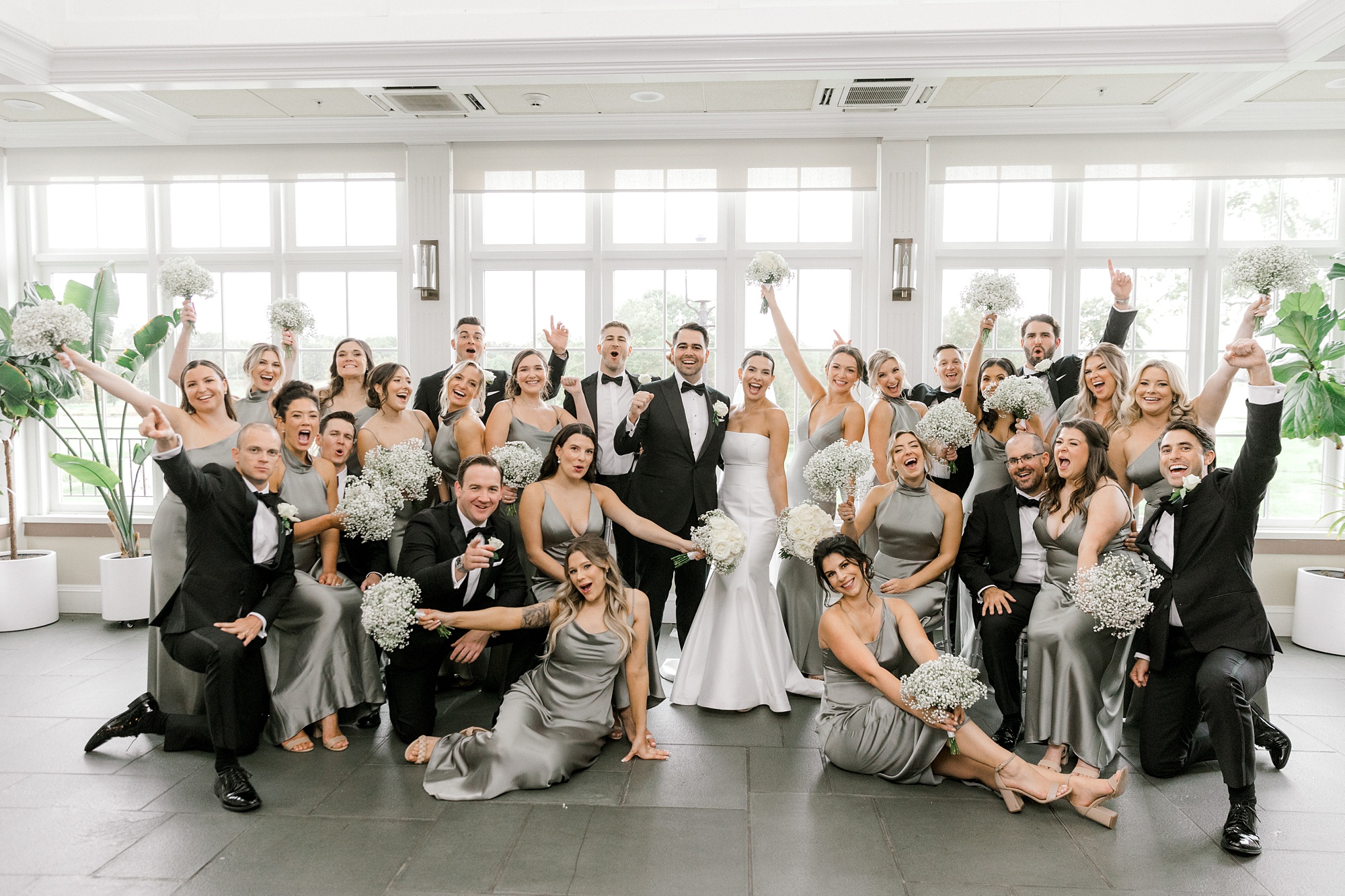 bride and groom cheer with wedding party in sage green and black attire