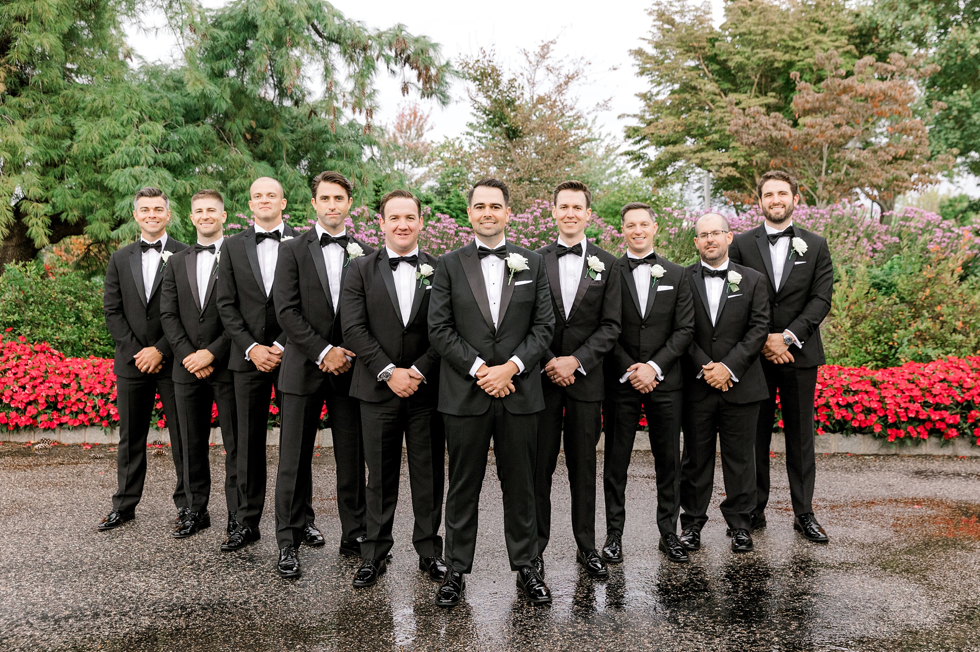 groom and groomsmen stand in V formation on wet patio at Fiddler’s Elbow Country Club 