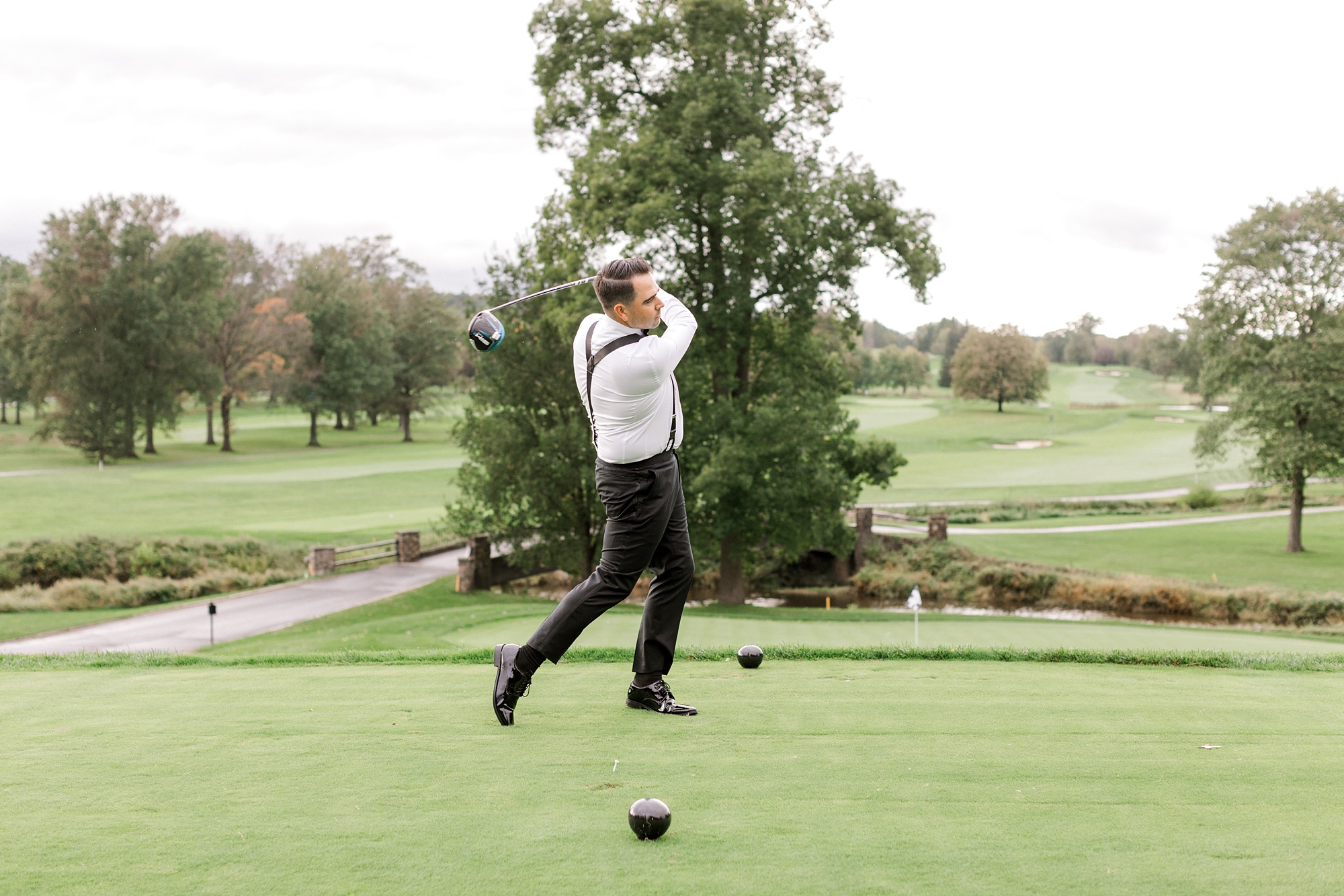 groom takes a swing on golf course at Fiddler’s Elbow Country Club 