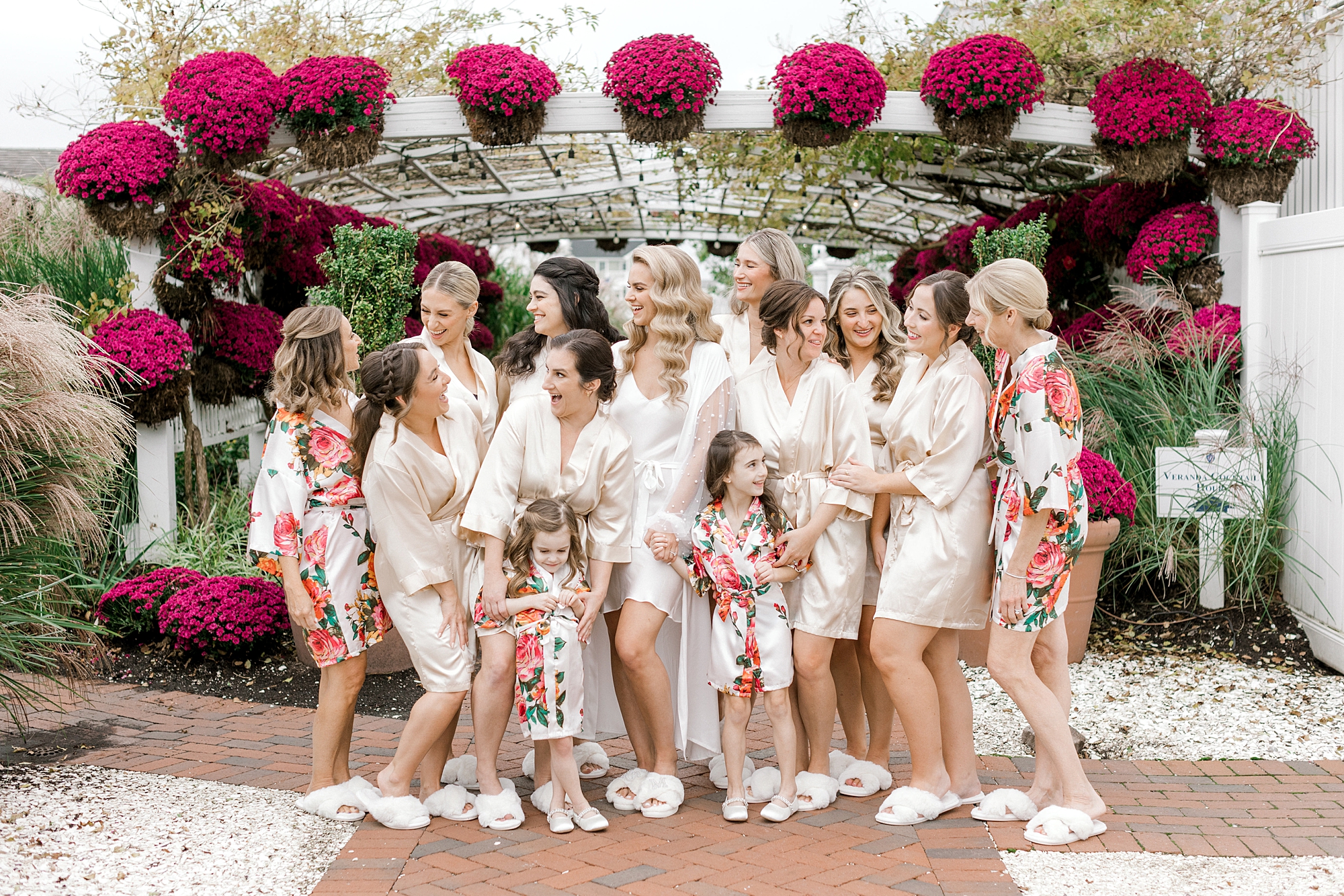 bride and bridesmaids in floral gowns pose under hanging pink flowers at Bonnet Island Estate