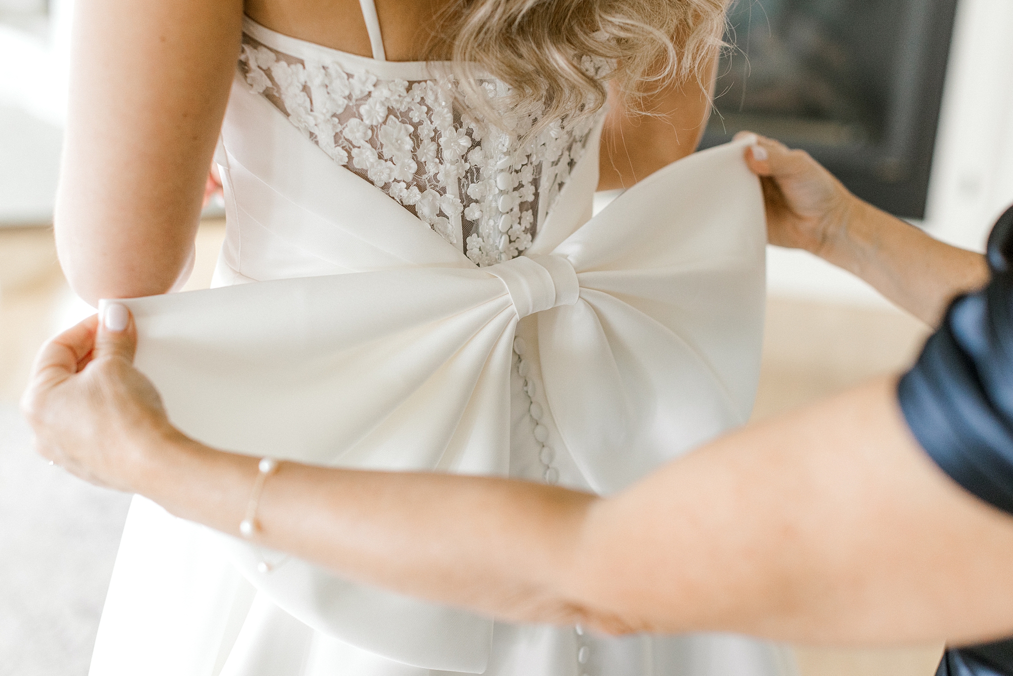 woman holds out bow on back of wedding dress