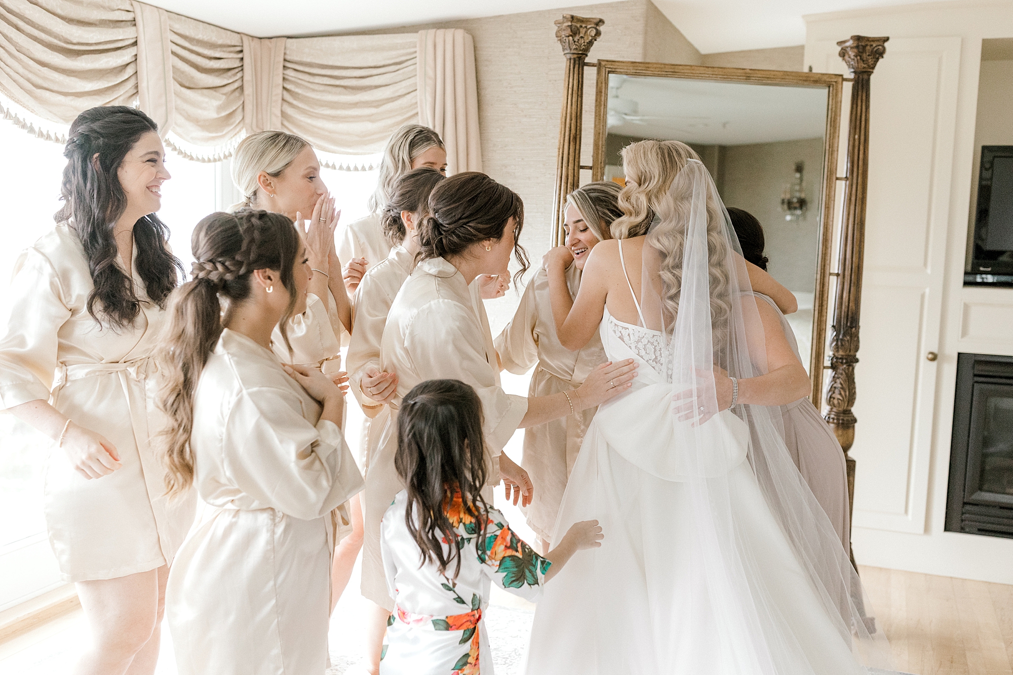 bridesmaids look at bride's wedding dress during prep