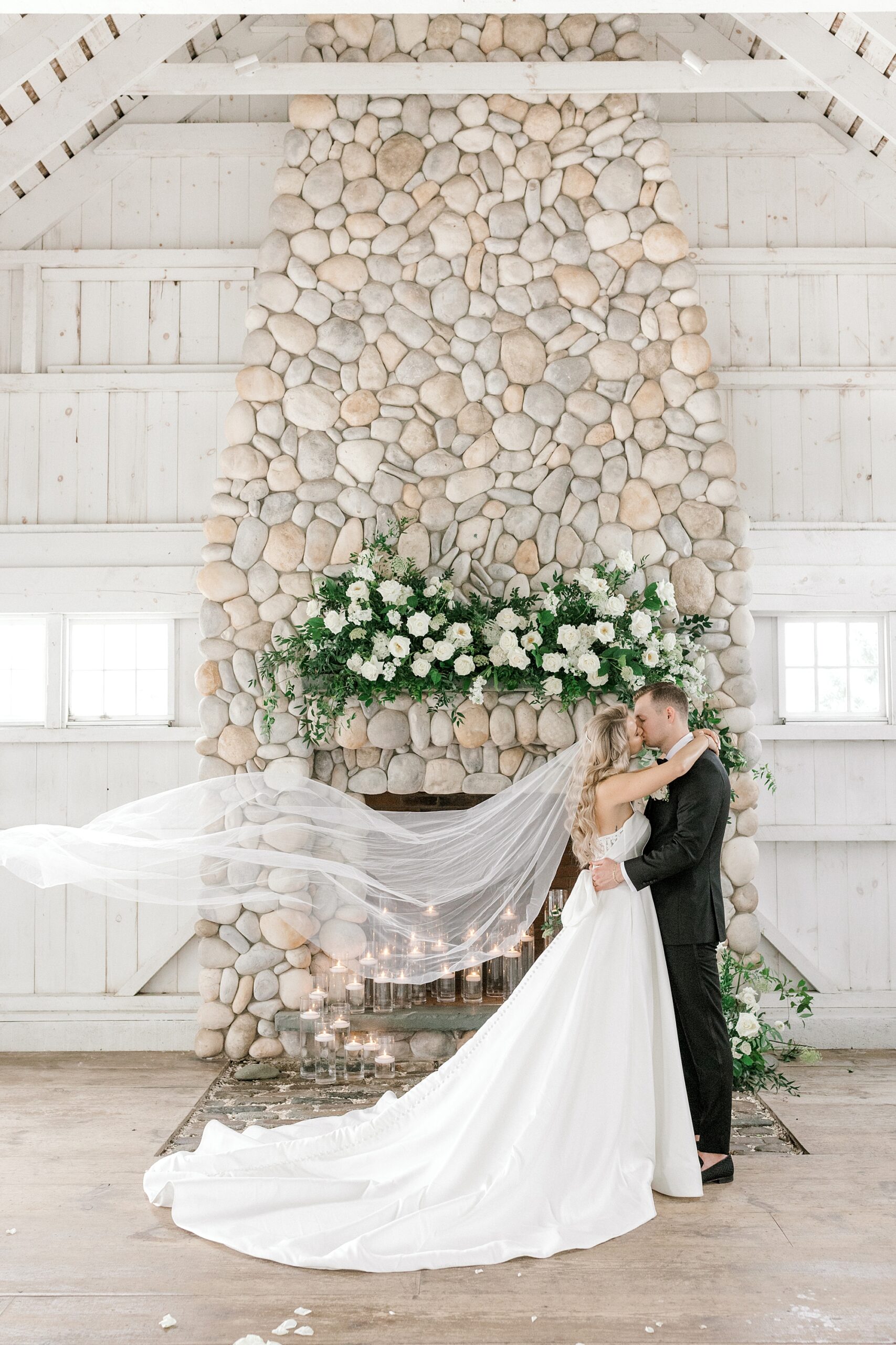 bride and groom kiss in front of stone fireplace inside Bonnet Island Estate
