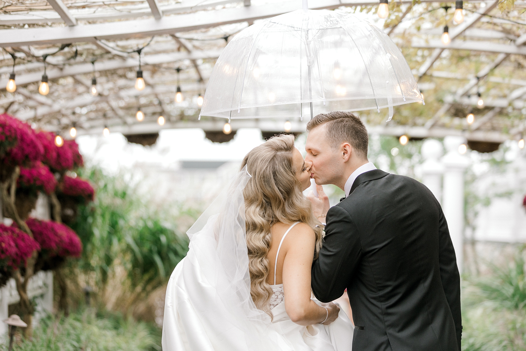 bride and groom kiss under clear umbrella outside Bonnet Island Estate