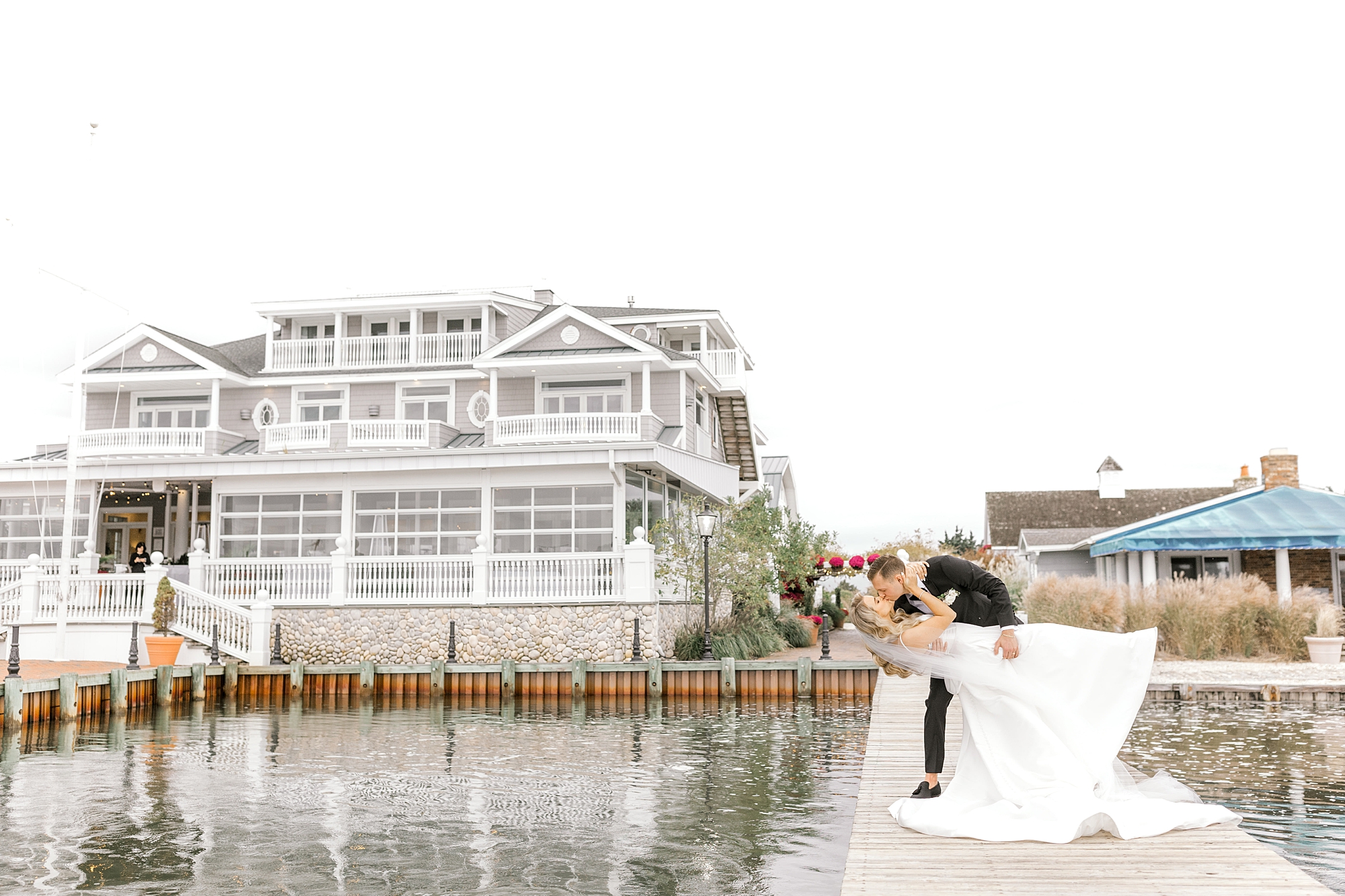 groom dips bride kissing her on dock outside Bonnet Island Estate
