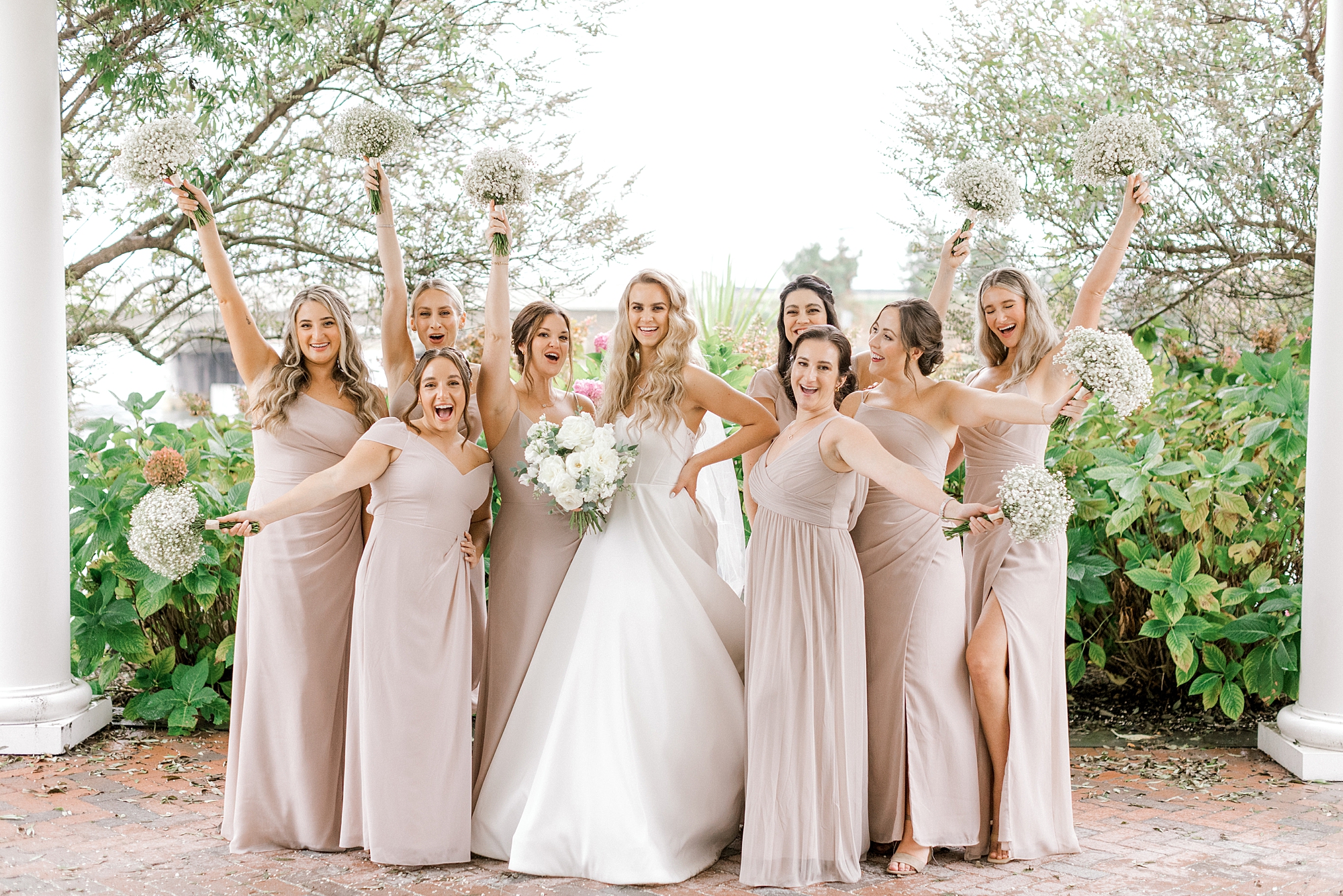 bride and bridesmaids hold up bouquets and laugh