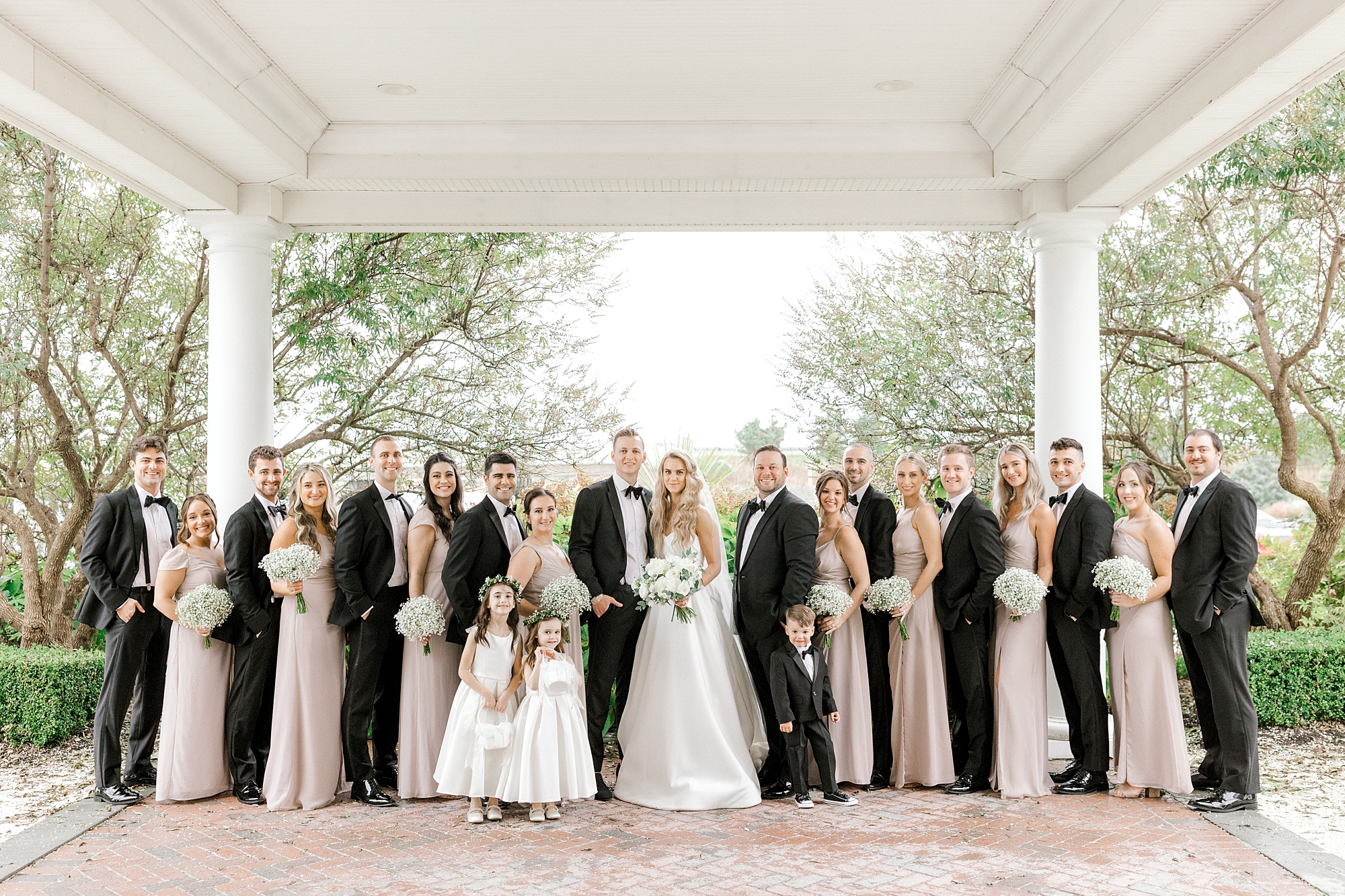 newlyweds pose with wedding party in pink and black around them
