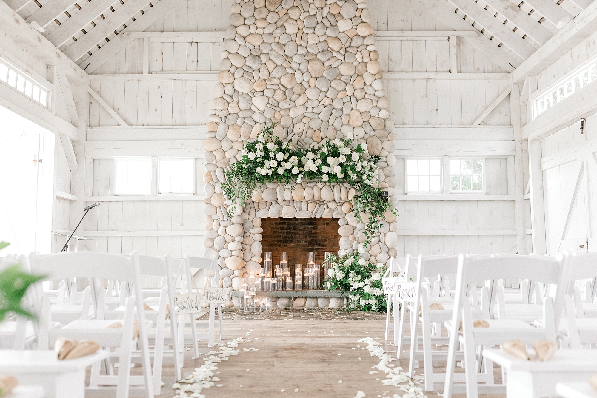 ceremony site in front of stone fireplace at Bonnet Island Estate with white flowers and greenery on mantel