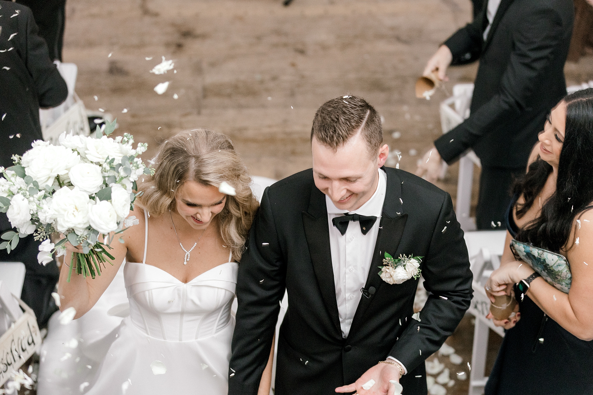 newlyweds smile as white flower petals fall around them at Bonnet Island Estate