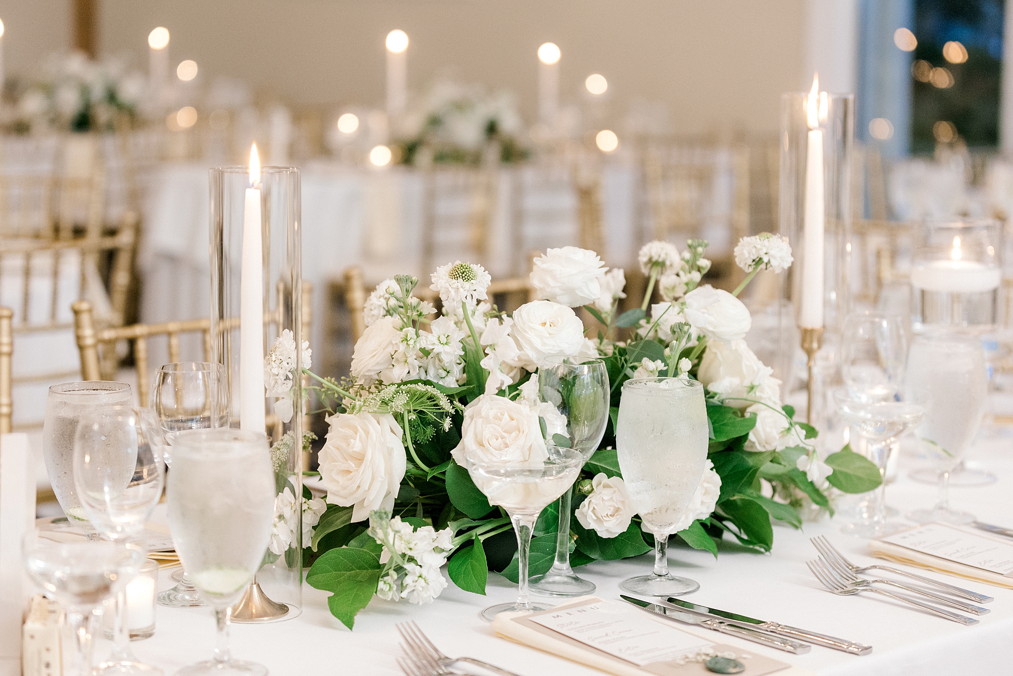white floral centerpieces with greenery and candles
