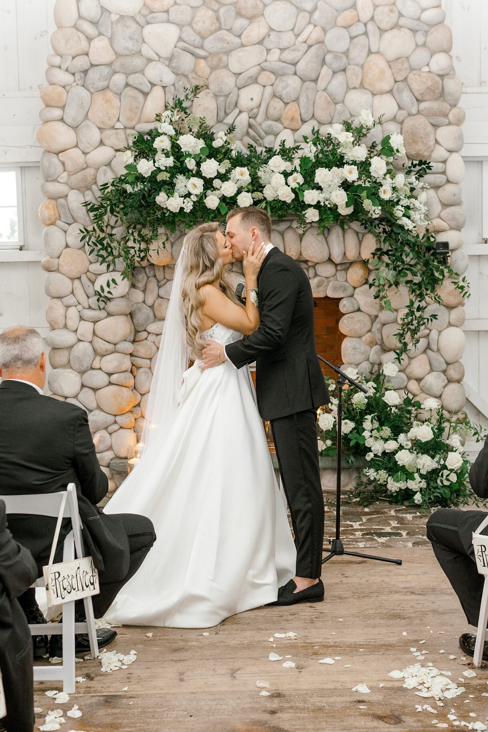 bride and groom kiss during wedding ceremony in front of stone fireplace inside Bonnet Island Estate