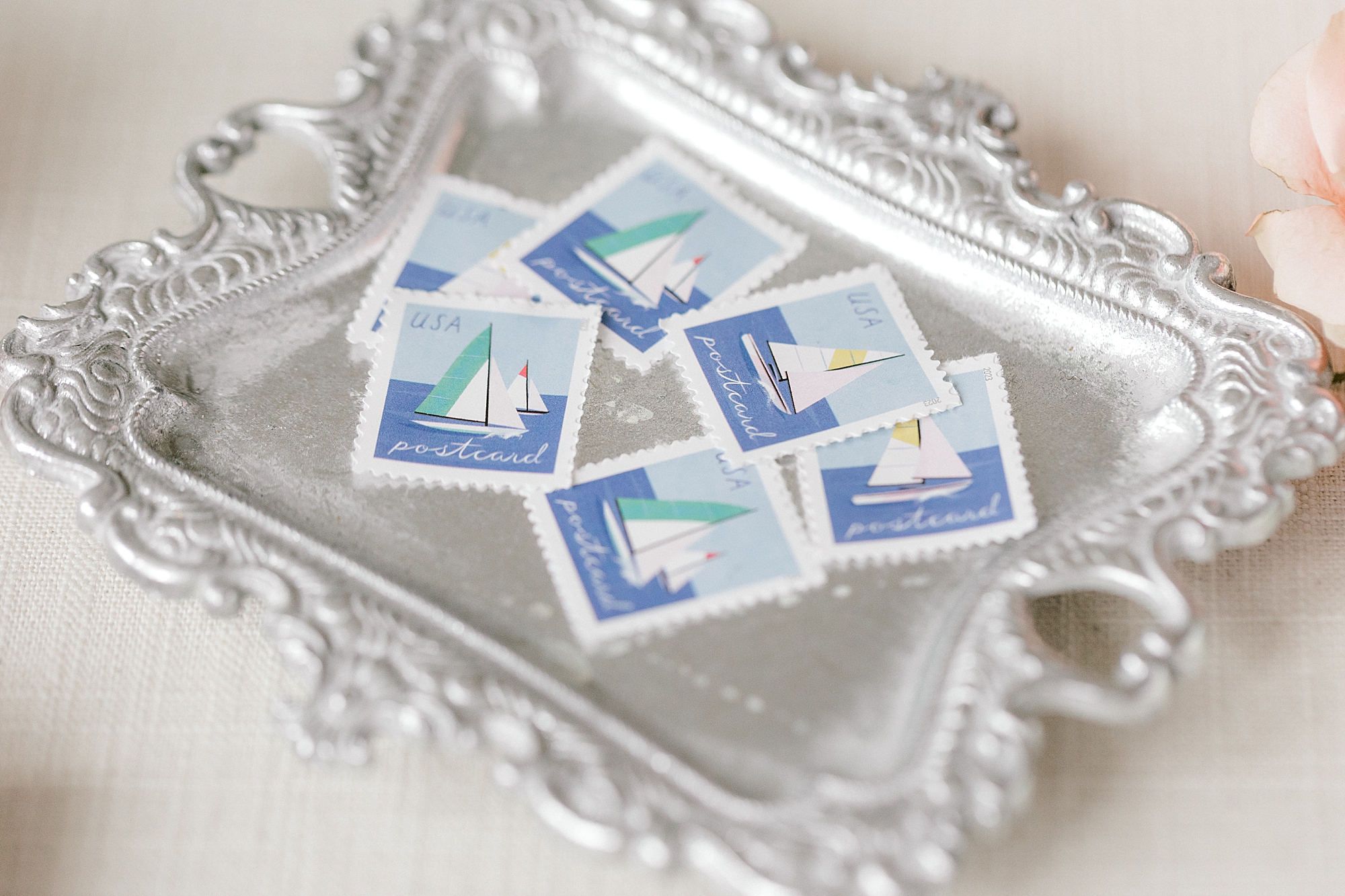 sailboat stamps lay on silver tray for coastal inspired wedding at Bonnet Island Estate