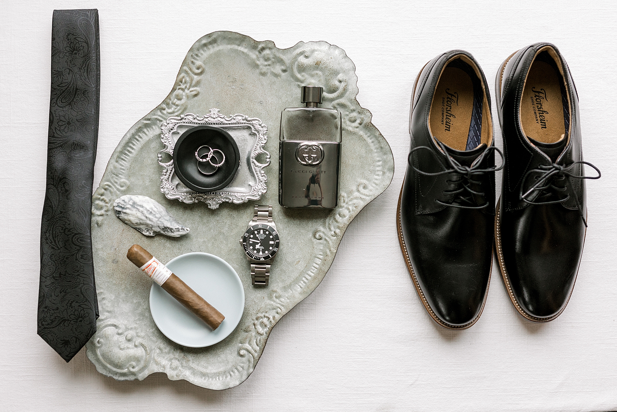 groom's black shoes and tie next to silver tray with details