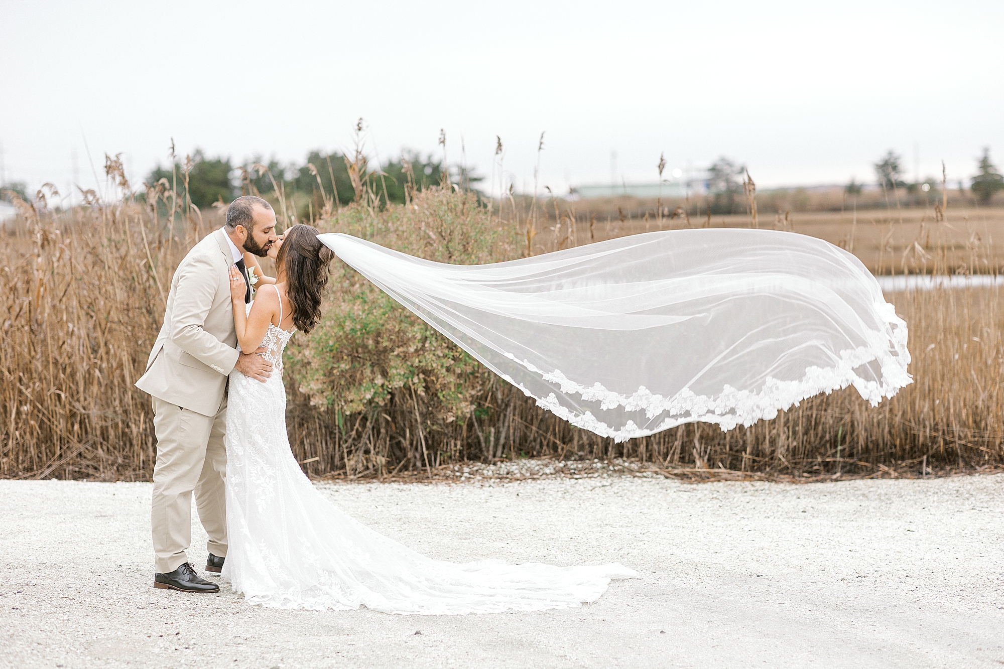 newlyweds kiss with veil floating behind them on Long Beach Island