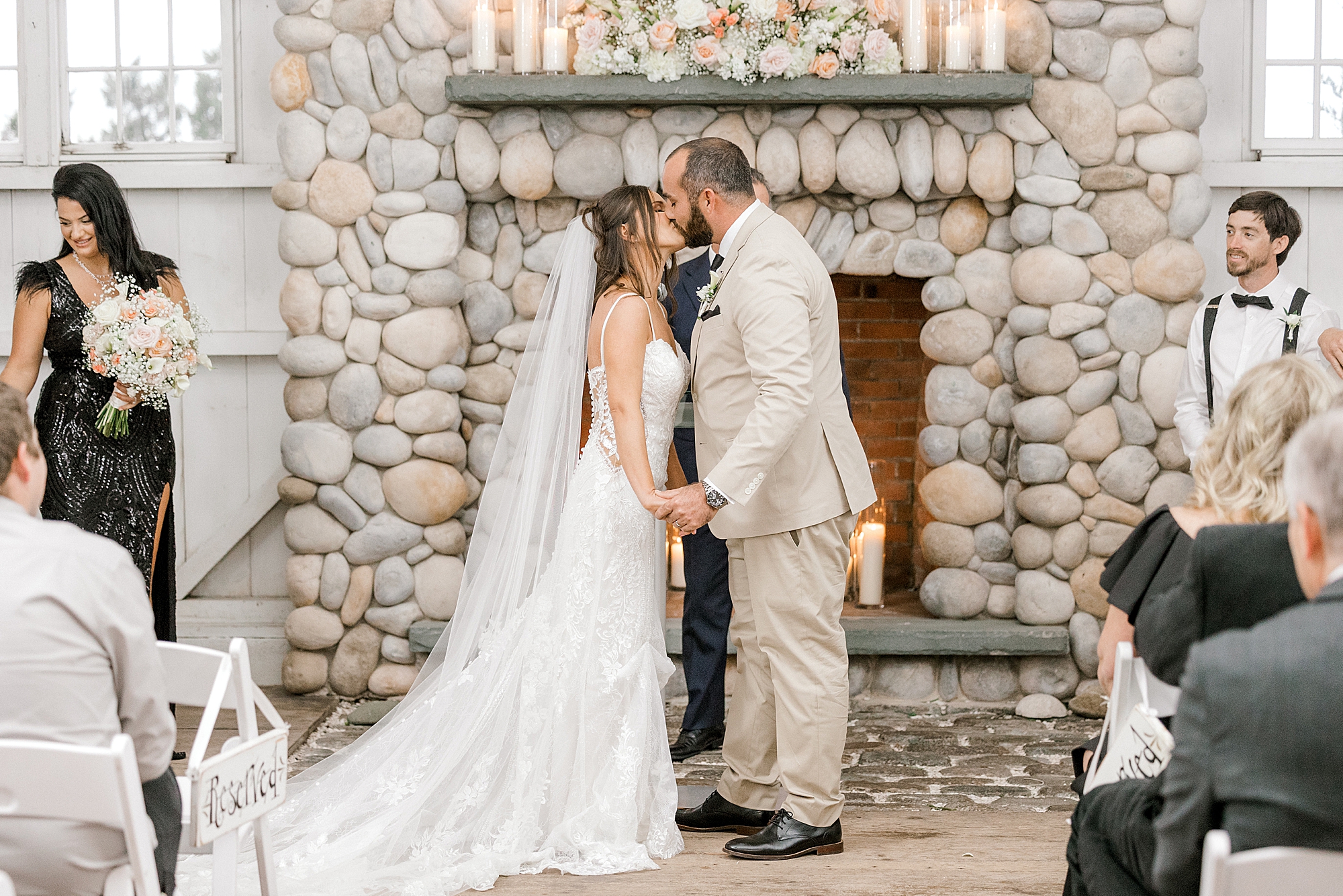 newlyweds kiss in front of stone fireplace at Bonnet Island Estate