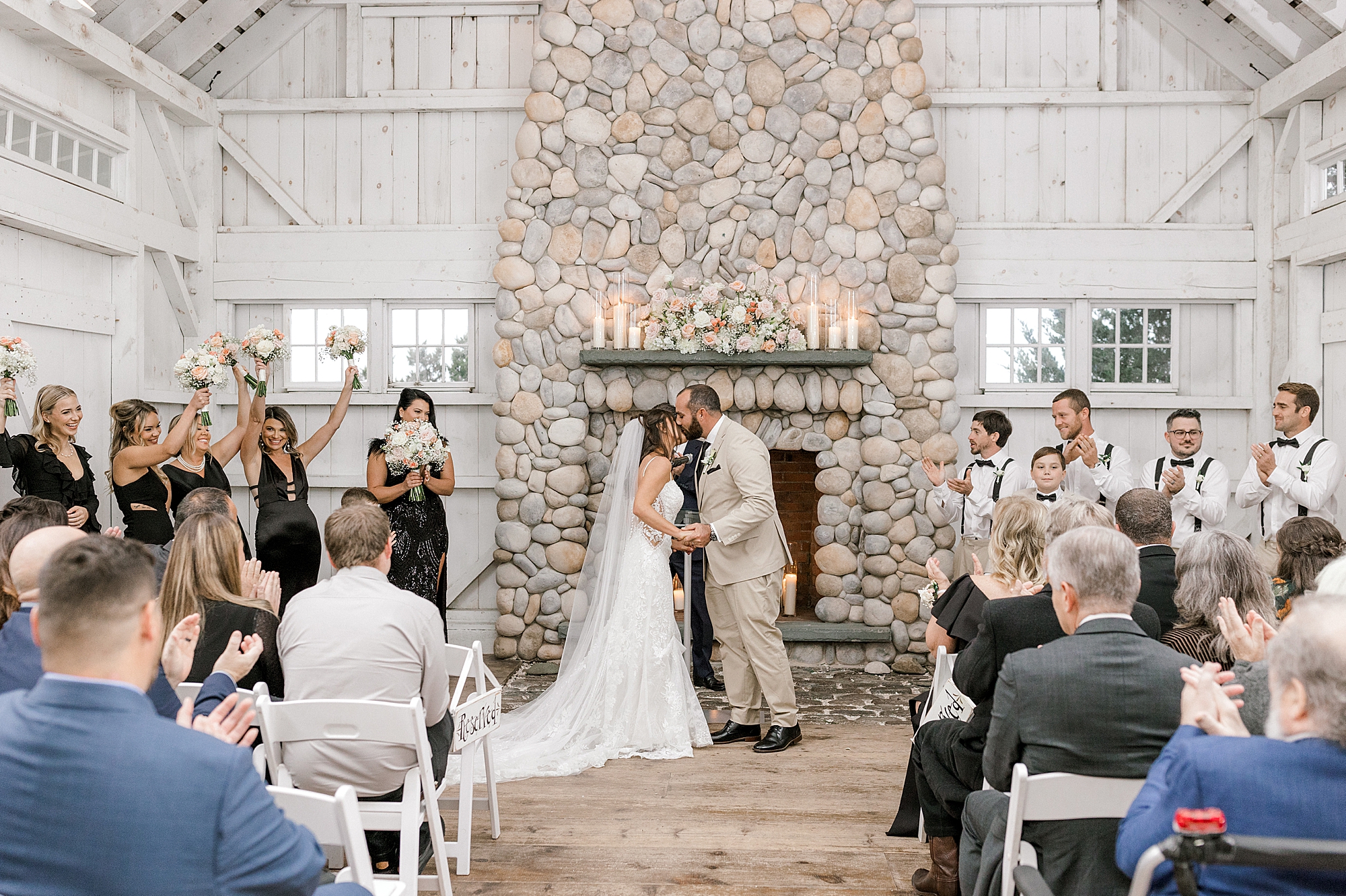 groom kisses bride's forehead in front of stone fireplace at Bonnet Island Estate