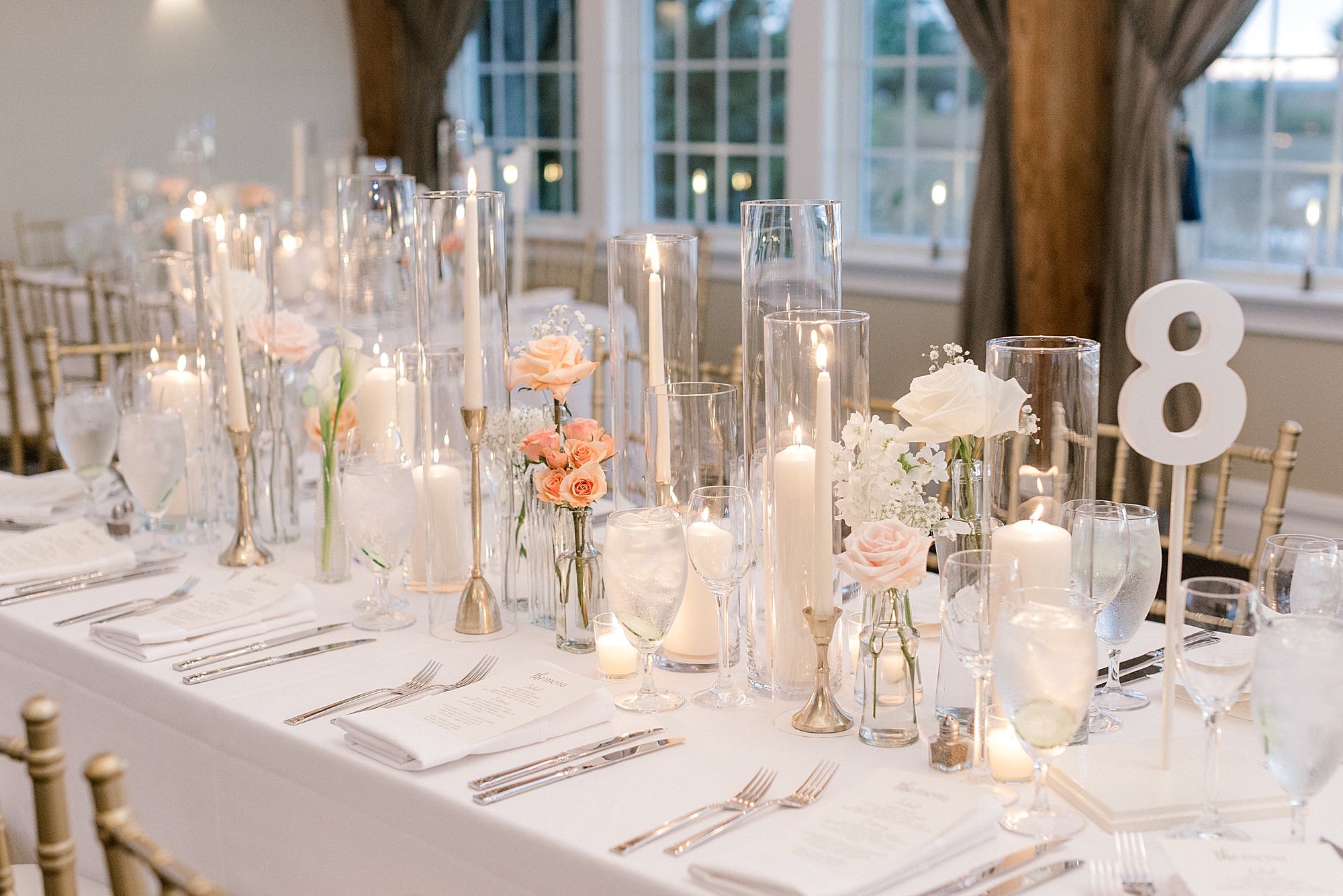 peach flowers, taper candles, and white candles rest on table at Bonnet Island Estate