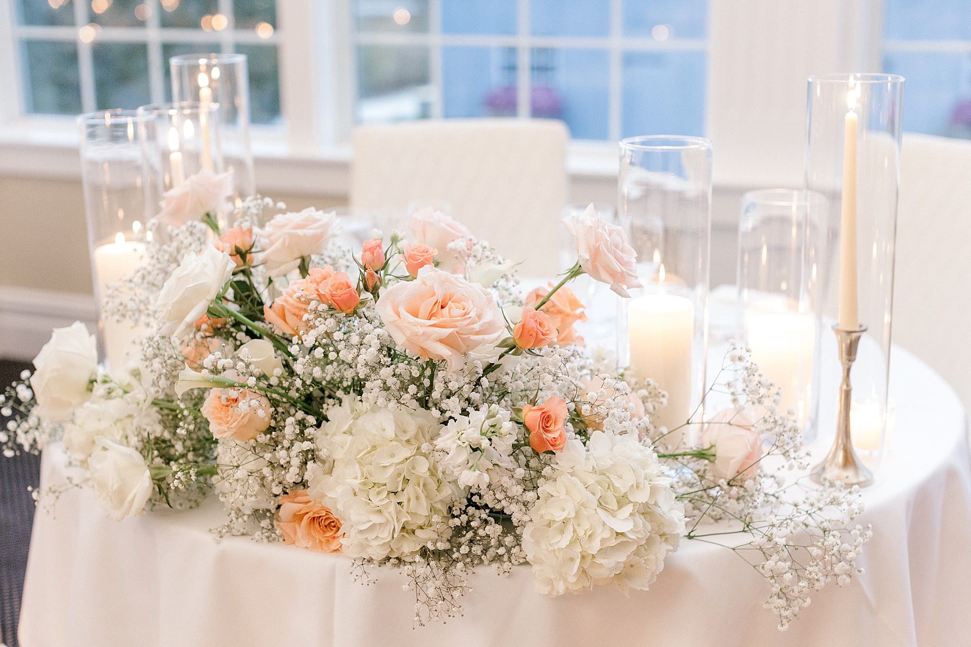 sweetheart table with peach and white flowers and baby's breath for summer wedding reception at Bonnet Island Estate