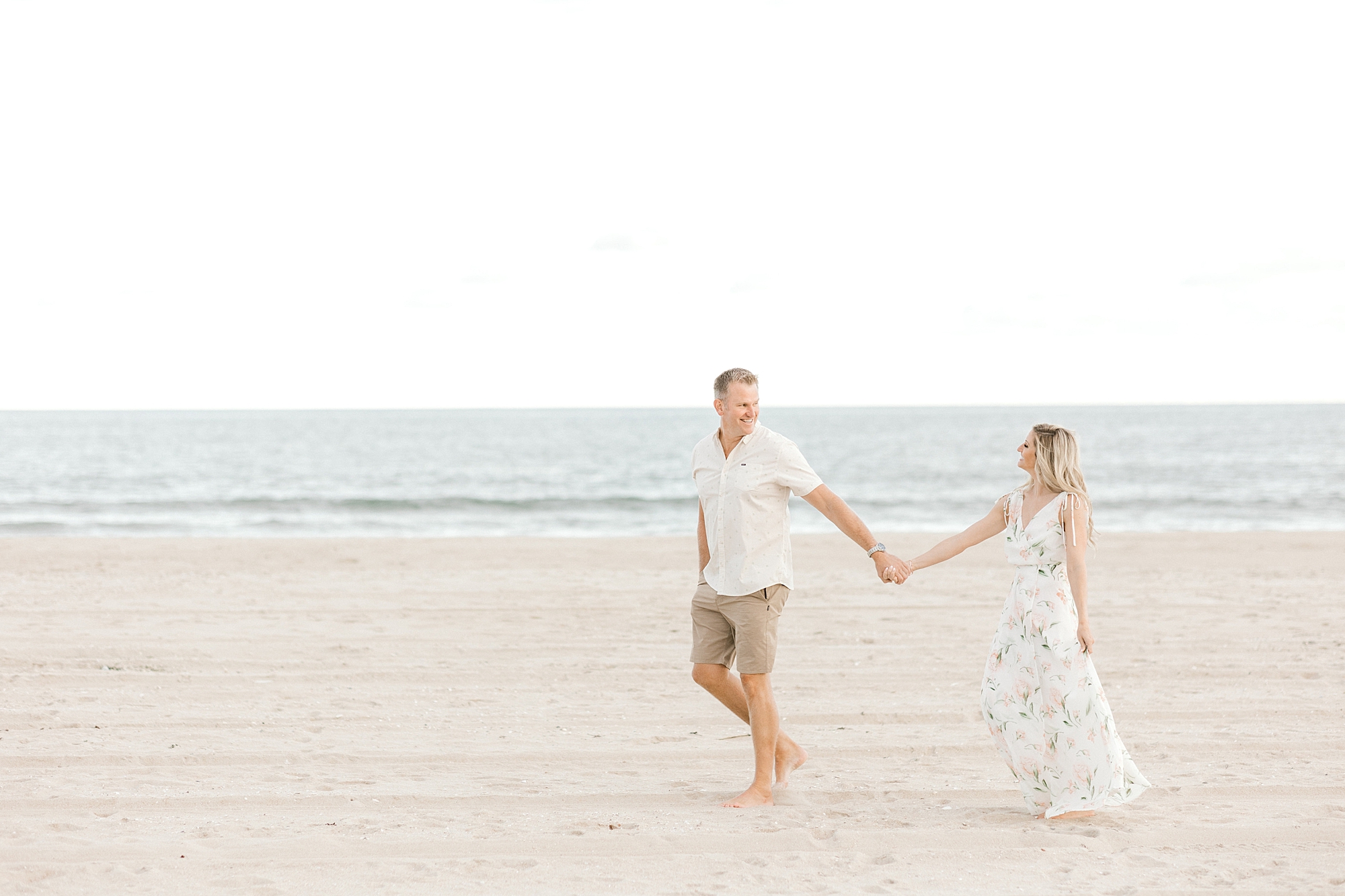 man and woman walk on beach during Long Beach Island engagement session