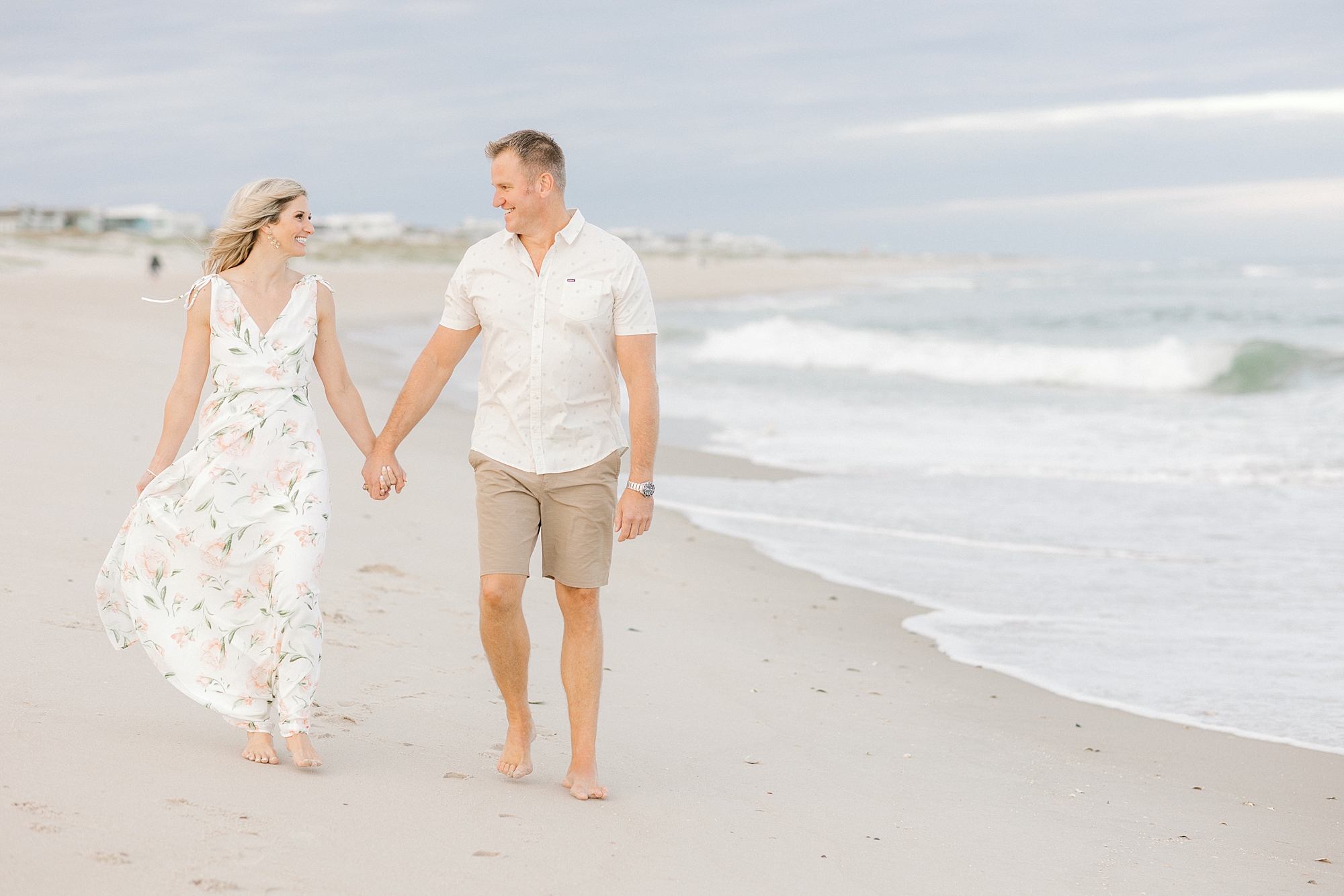engaged couple holds hands walking on Brant Beach on LBI