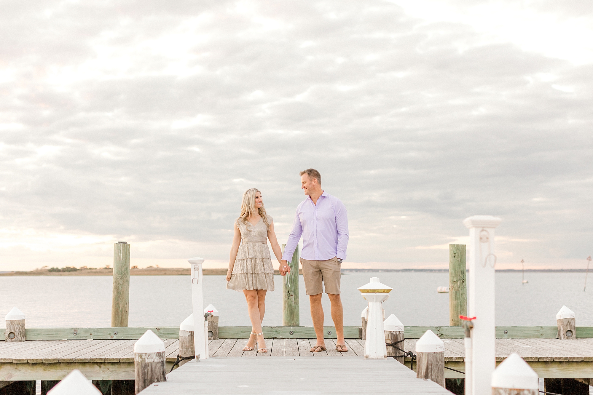 couple holds hands at sunset on dock during Long Beach Island engagement session