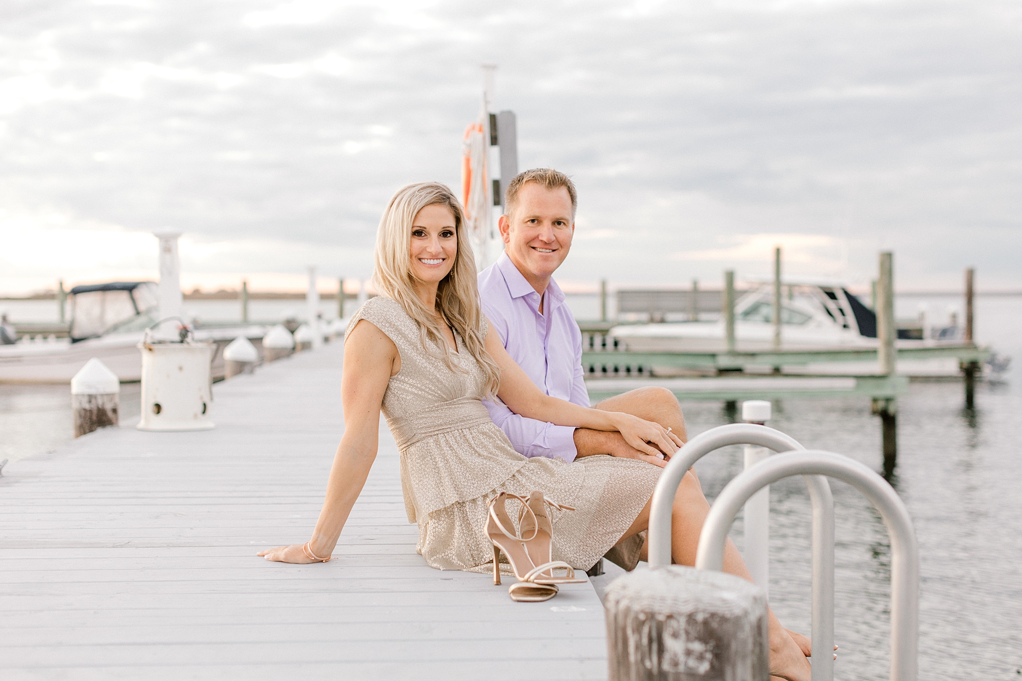 man and woman sit on dock during summer Long Beach Island engagement session