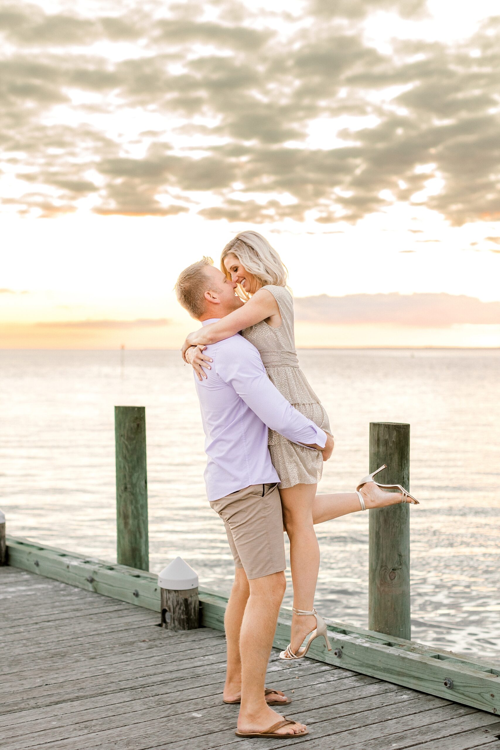 man lifts up woman during Brant Beach engagement session on dock
