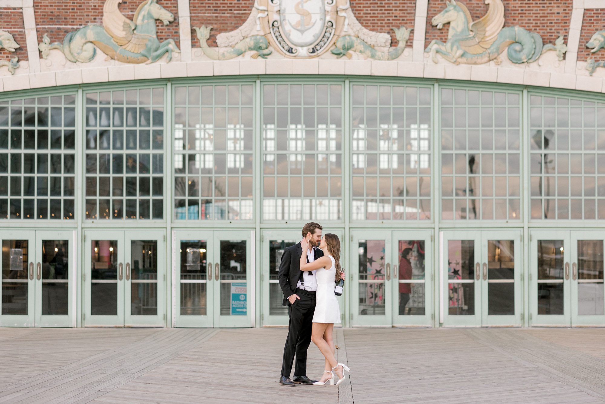 engaged couple kisses in front of historic carousel at Asbury Park
