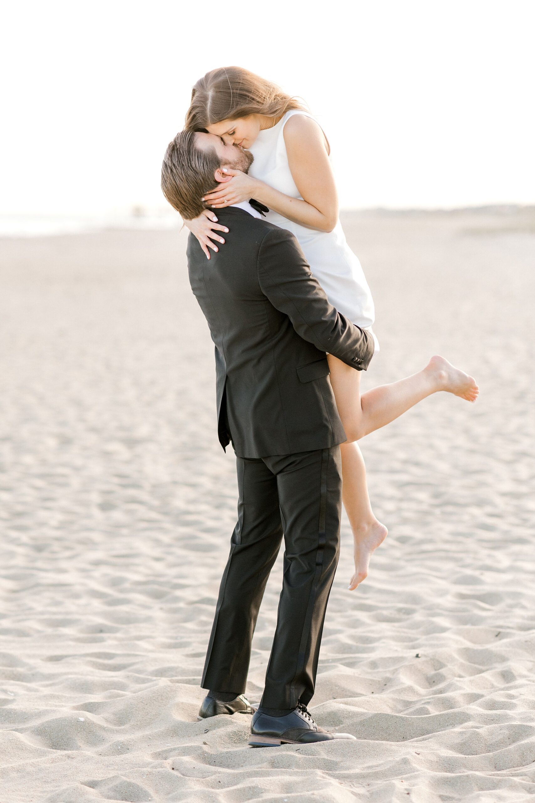 man lifts up bride on beach in Asbury Park