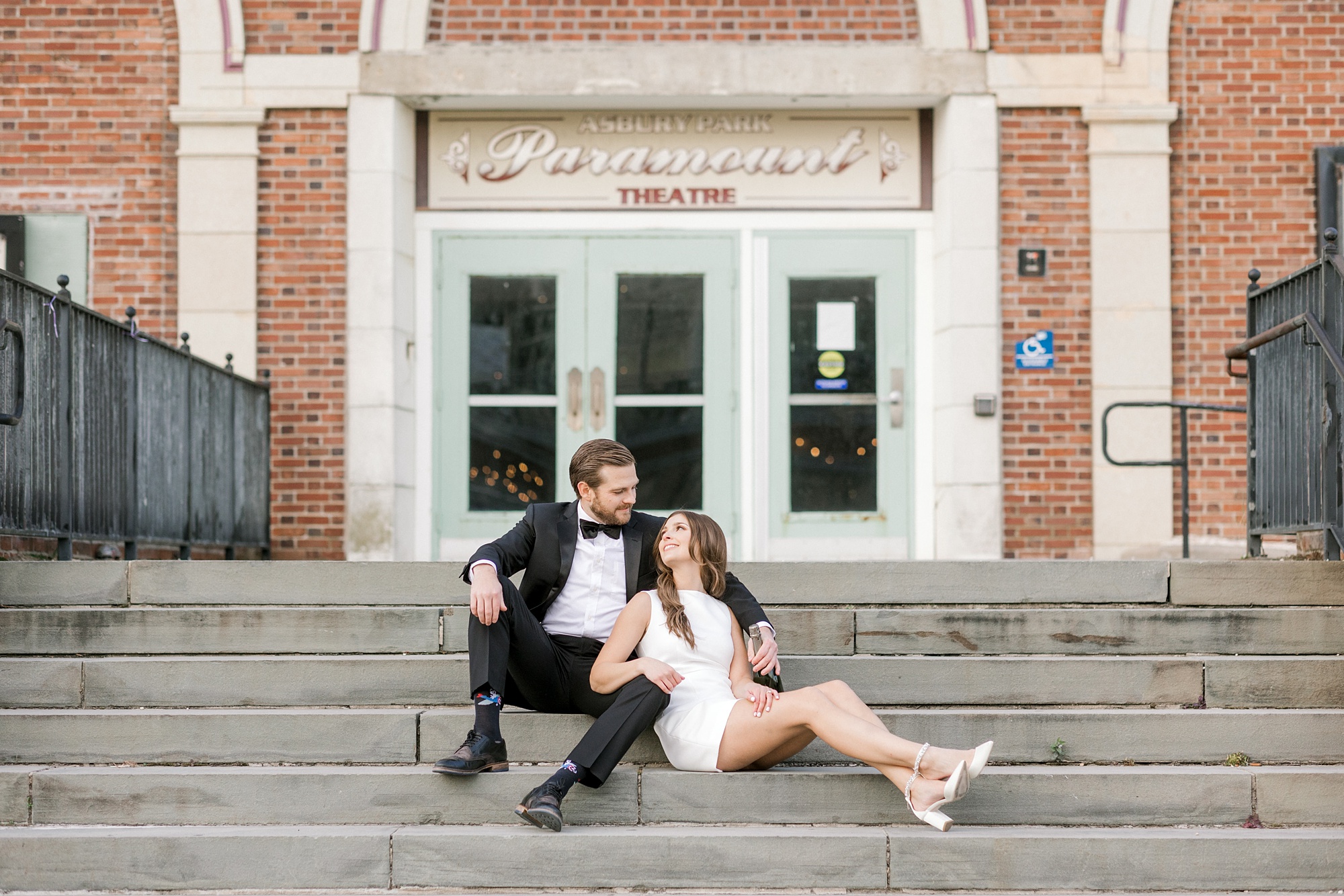 engaged couple sits on steps outside the Paramount Theatre in Asbury Park NJ