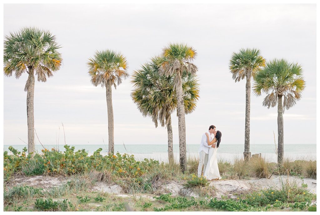 couple kissing sounded by palm trees at Lido Key Beach