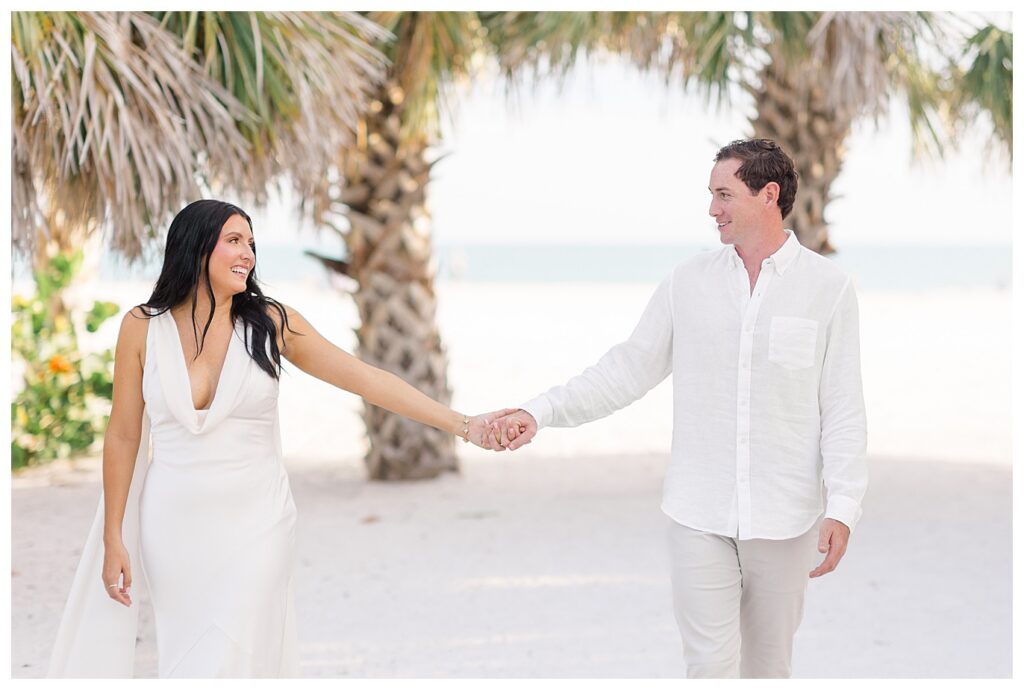 a couple walking holding hands with palm trees in the background