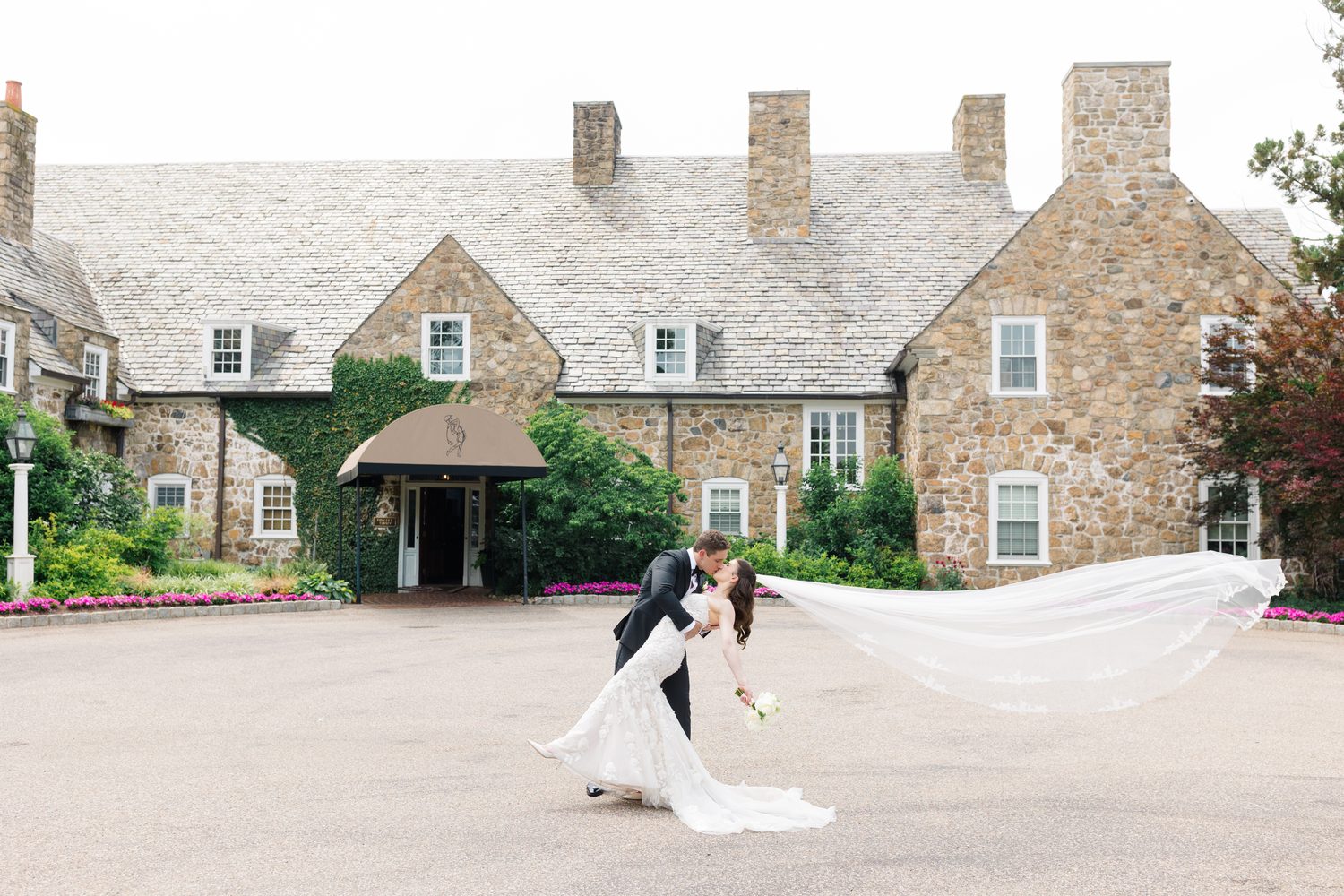 Will dipping Abby for a kiss with her veil flying in front of the stone clubhouse, NJ wedding photographer Susan Elizabeth Photography